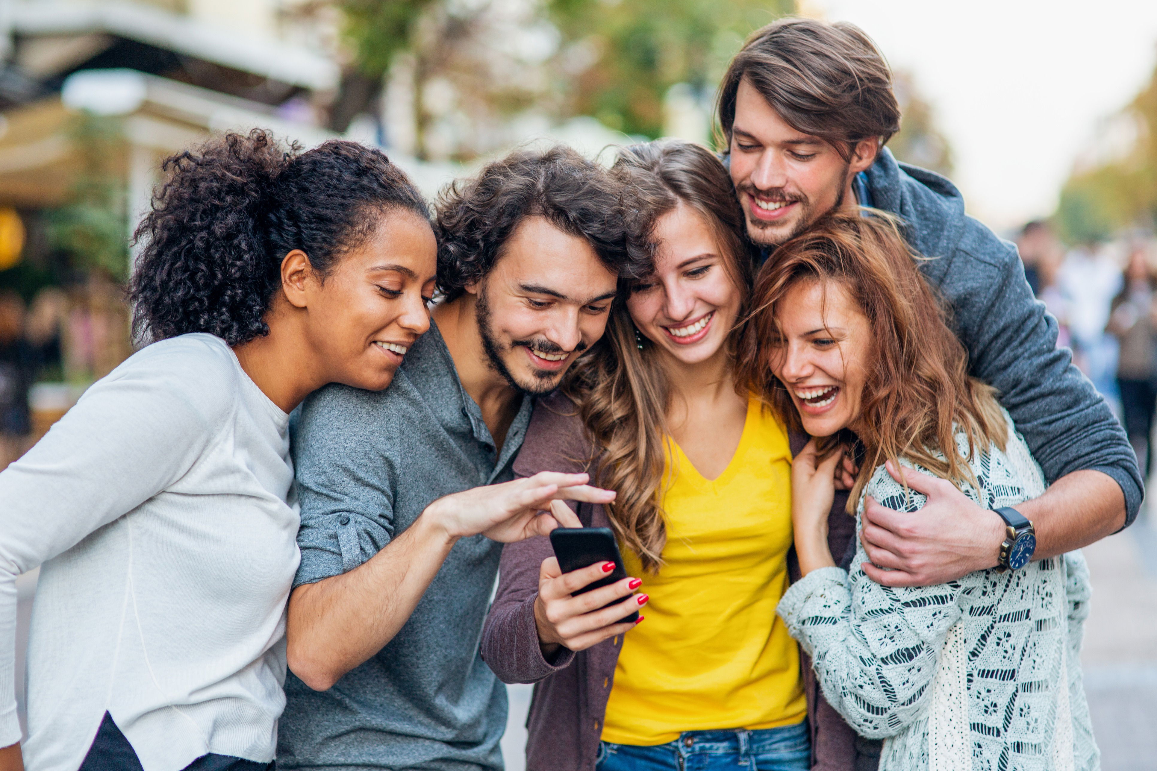 A diverse group of young adults standing together in an outdoor setting, engaged with their smartphones, symbolizing the power of digital outreach and online community engagement for modern evangelism. Their shared activity highlights connection, collaboration, and communication through digital tools.