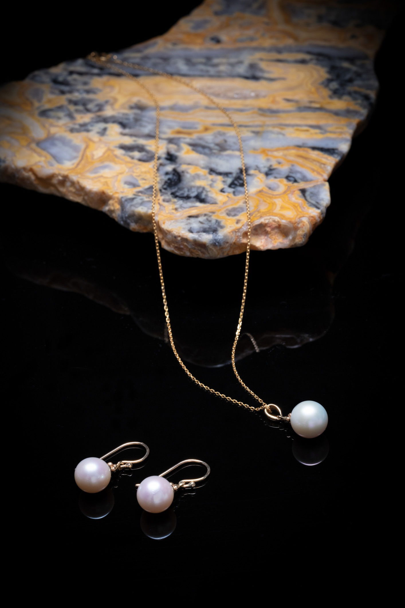 Dainty black and gold necklace dangling over black hand sculpture