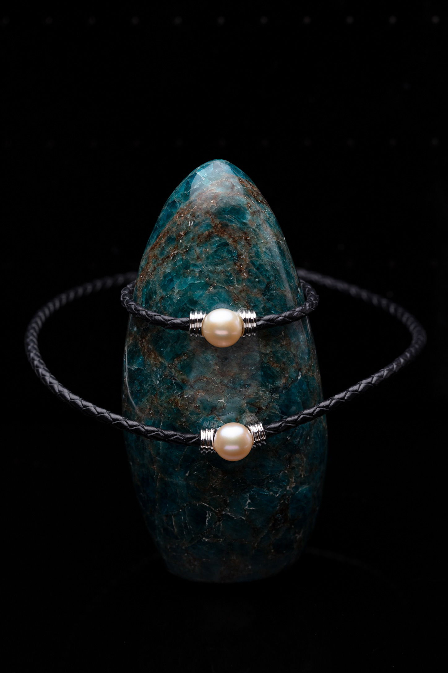 black leather bracelets hovering around a teal crystal