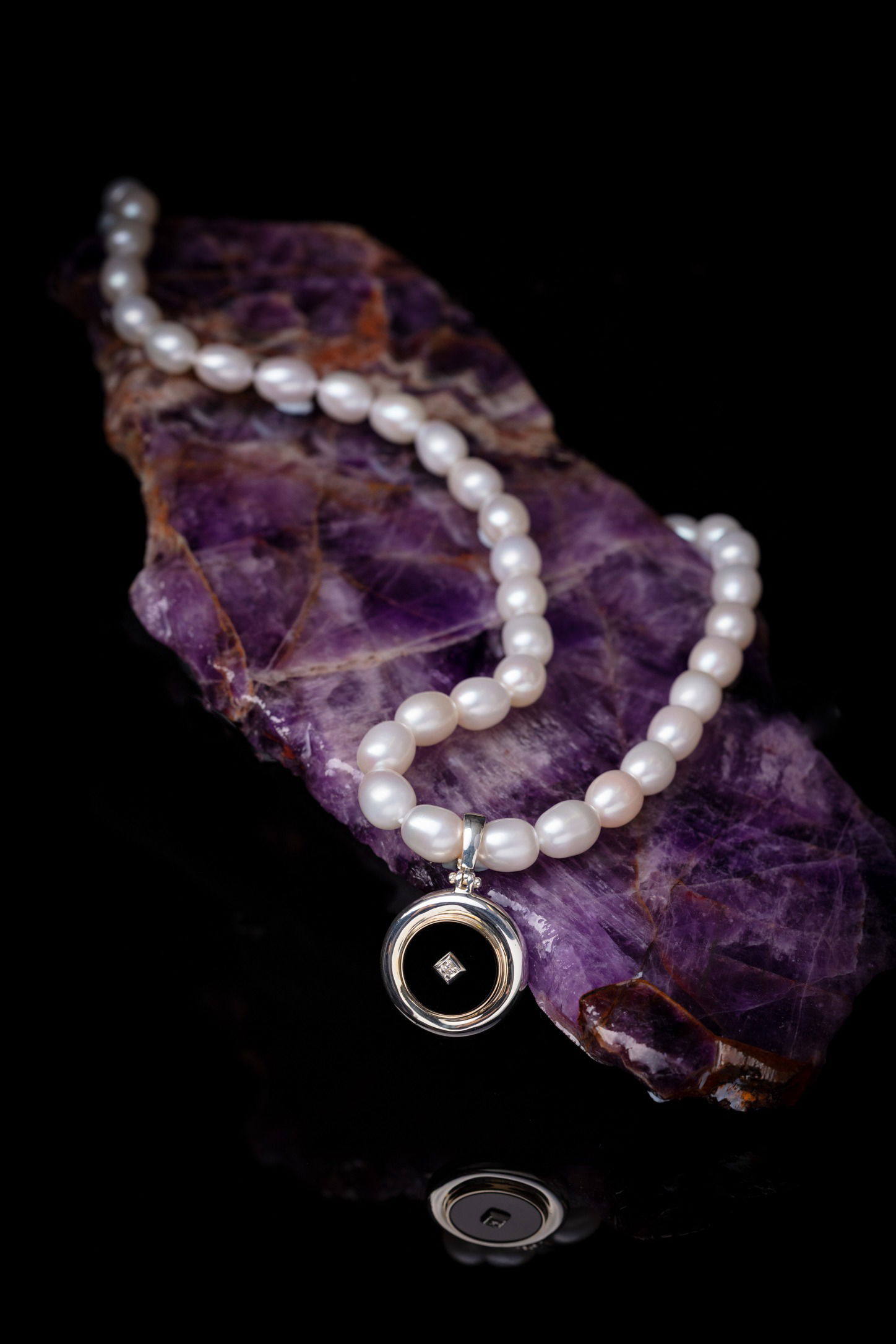 Pearl necklace layed out on a purple crystal